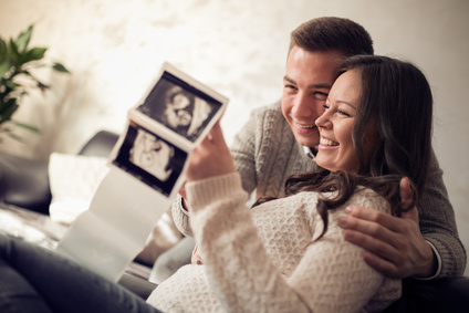 Junges schwangeres Paar schaut sich Ultraschallbild an