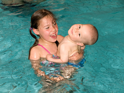 *Mädchen trägt Kleinkind im Schwimmbecken (Adobe Stock 31901479)